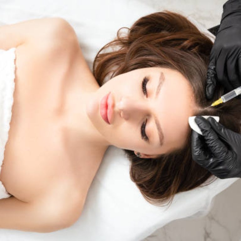 Mesotherapy,  vitamin injections in head skin of hair area. Professional hair loss treatment. Close up view of woman head and doctor's hands with syringe. View above.